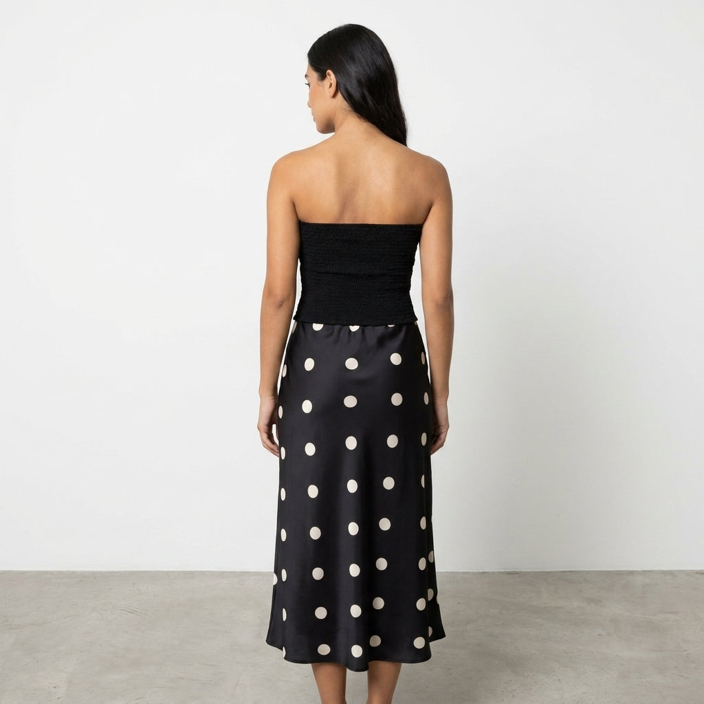 Woman in a black strapless top and polka dot skirt, facing away.