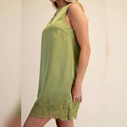 Woman in a sleeveless green dress with lace hem.