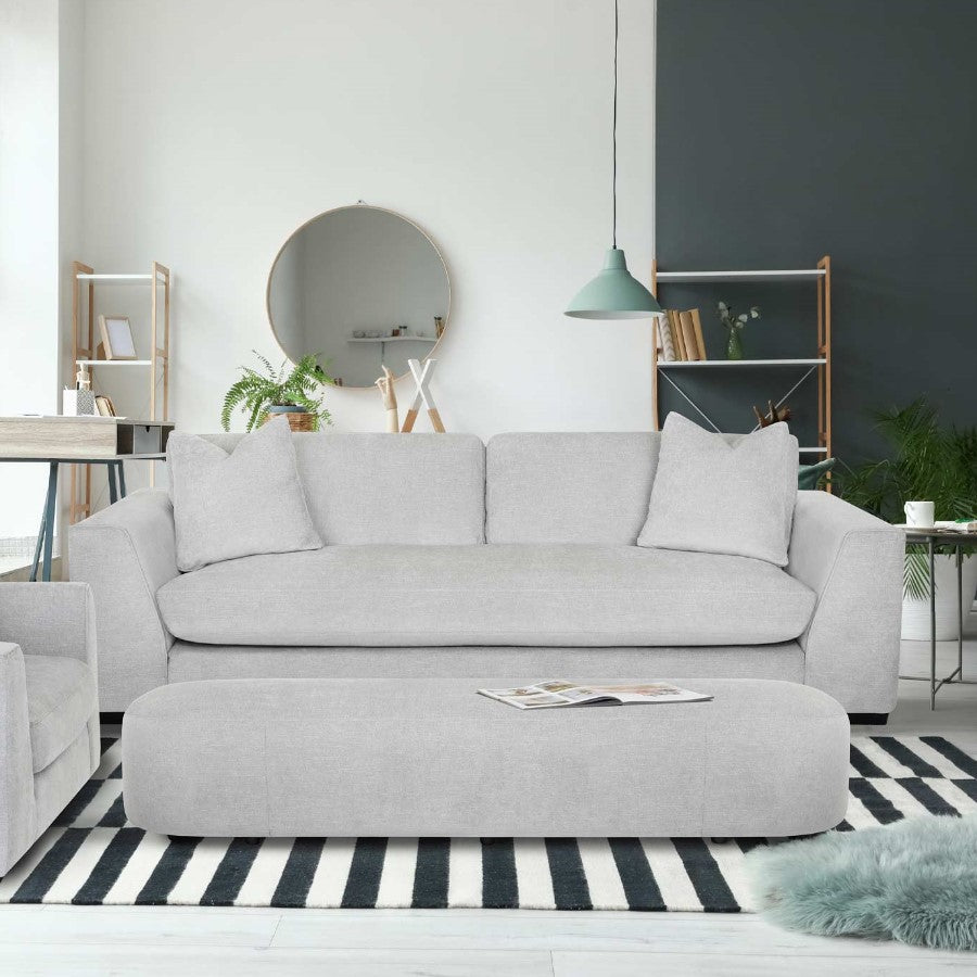 Modern living room with gray sofa, striped rug, and round mirror.