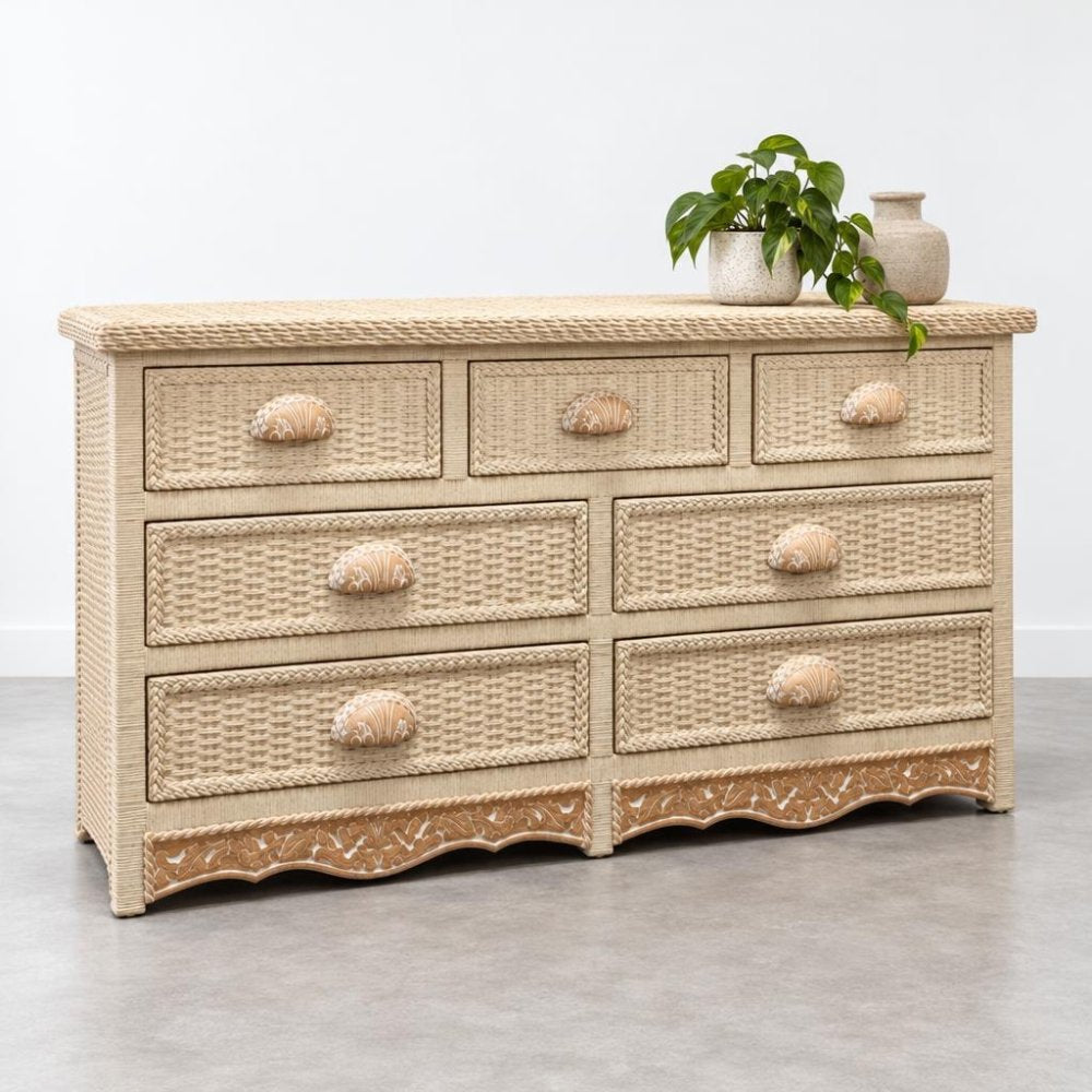 A woven wicker dresser with seven drawers, topped with a leafy plant and ceramic vase.