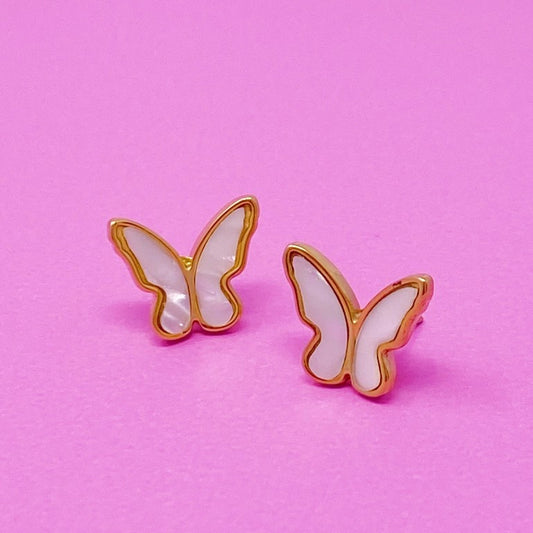 Gold-edged butterfly earrings on a pink background.