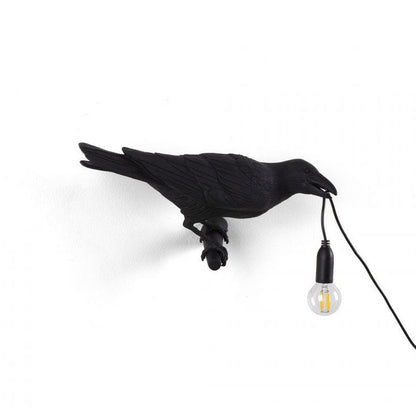 Black bird-shaped lamp holding a bulb on white background.