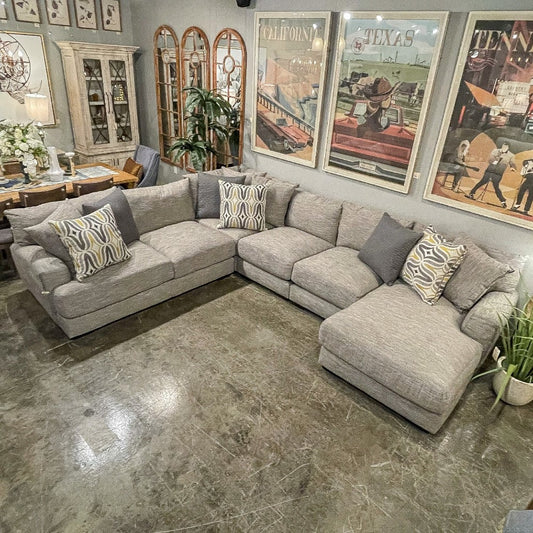 Gray sectional sofa with patterned cushions in a cozy living room.
