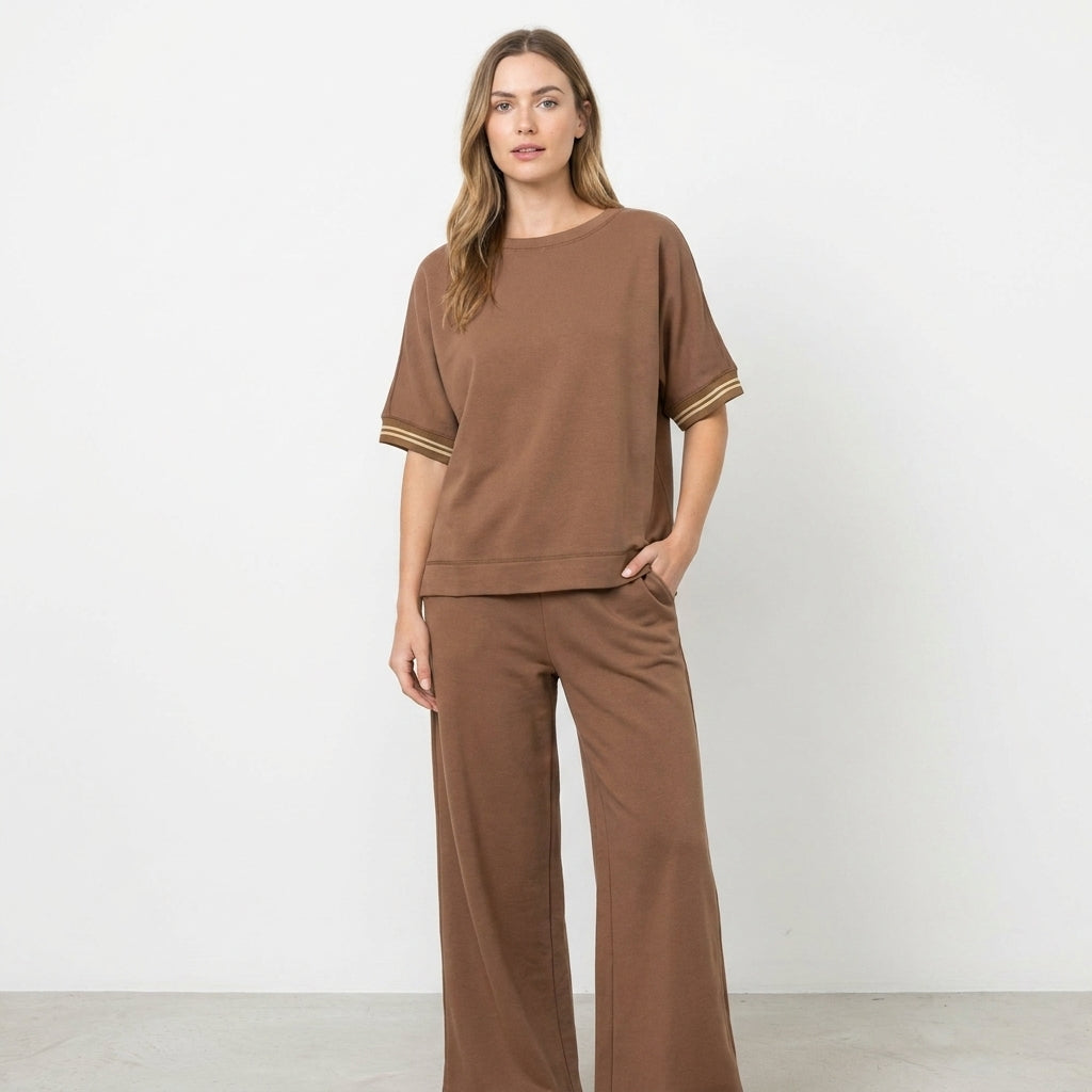 Woman in a brown loungewear set against a plain background.