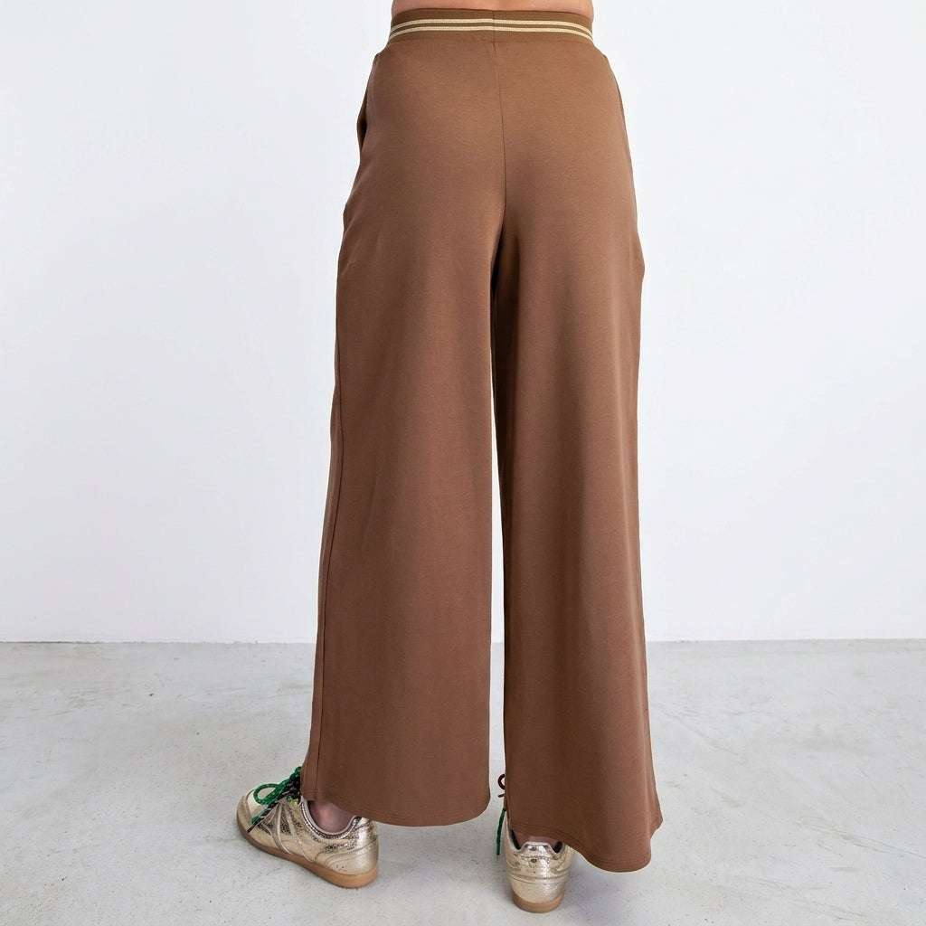 Brown wide-leg pants paired with gold sneakers.