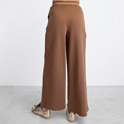 Brown wide-leg pants paired with gold sneakers.