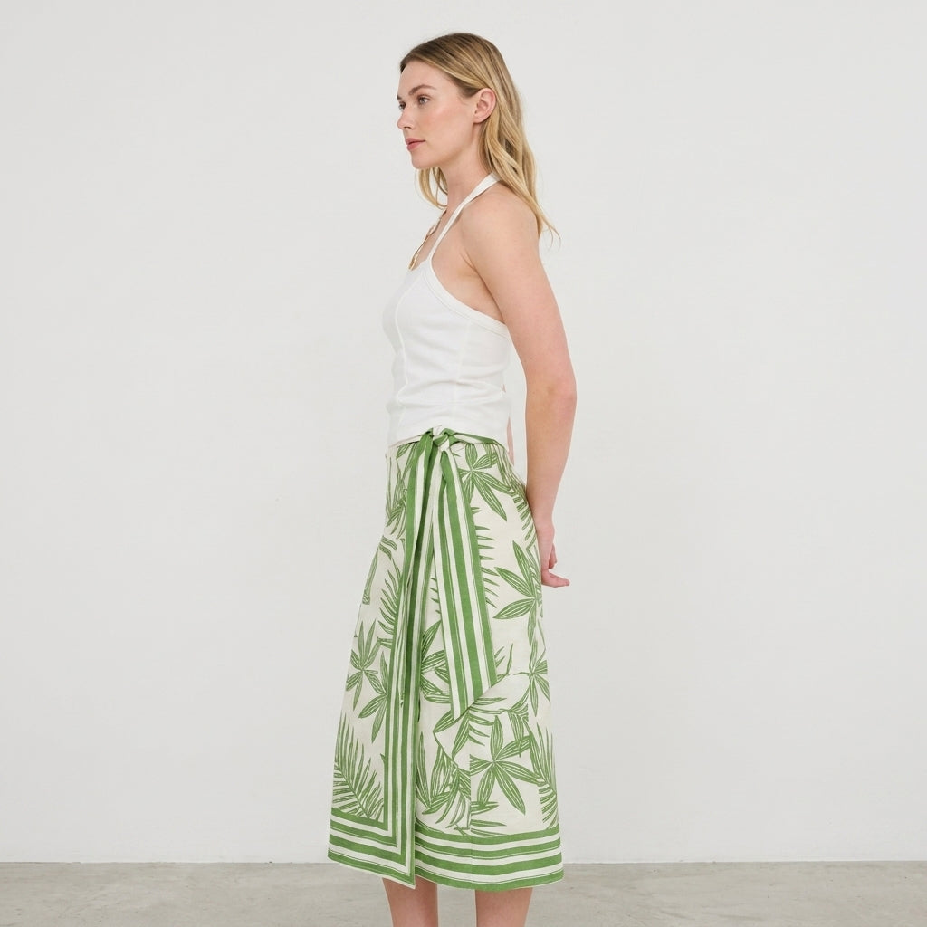 Woman in a white top and green patterned skirt, side profile.
