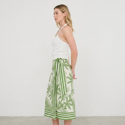 Woman in a white top and green patterned skirt, side profile.