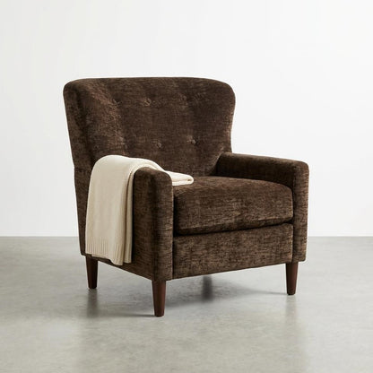 Brown armchair with cream blanket, on a gray floor.