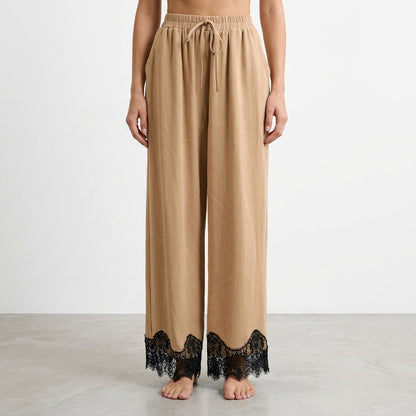 Beige wide-leg pants with black lace trim at the hem.