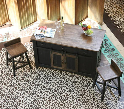 Wooden island with stools on a patterned tile floor; wine, fruit, and magazine on top.