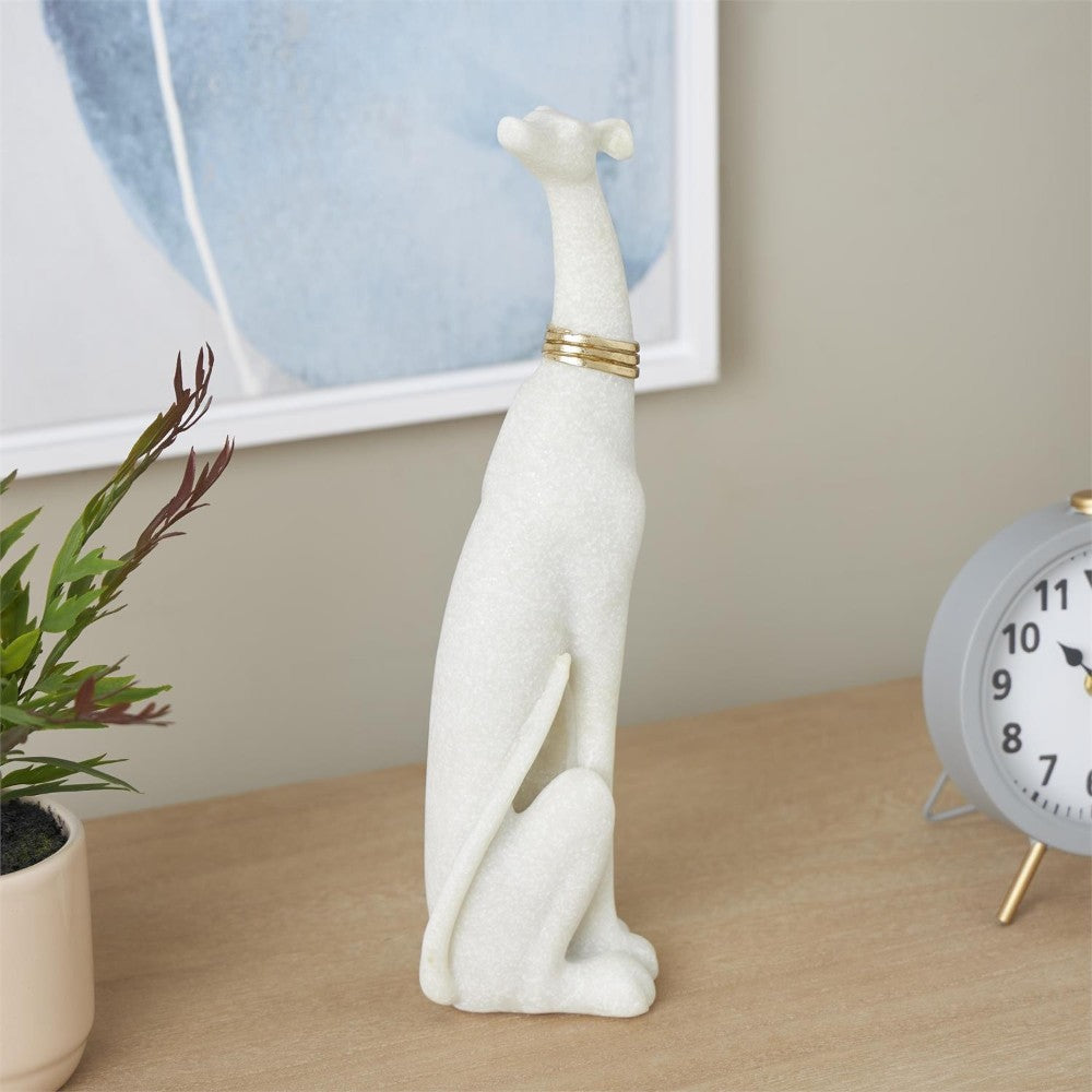 White dog statue on desk with clock and plant.
