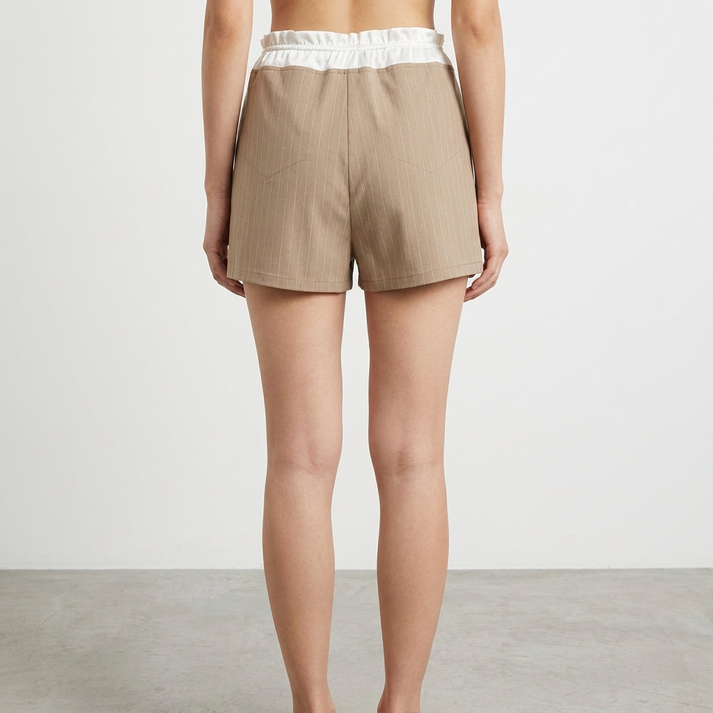 Person wearing beige pinstripe shorts with a white waistband, seen from the back.