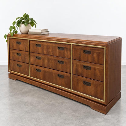 Wooden dresser with 9 drawers, topped with a plant and books.