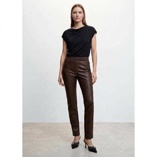 Woman in black top and leather pants, standing confidently.