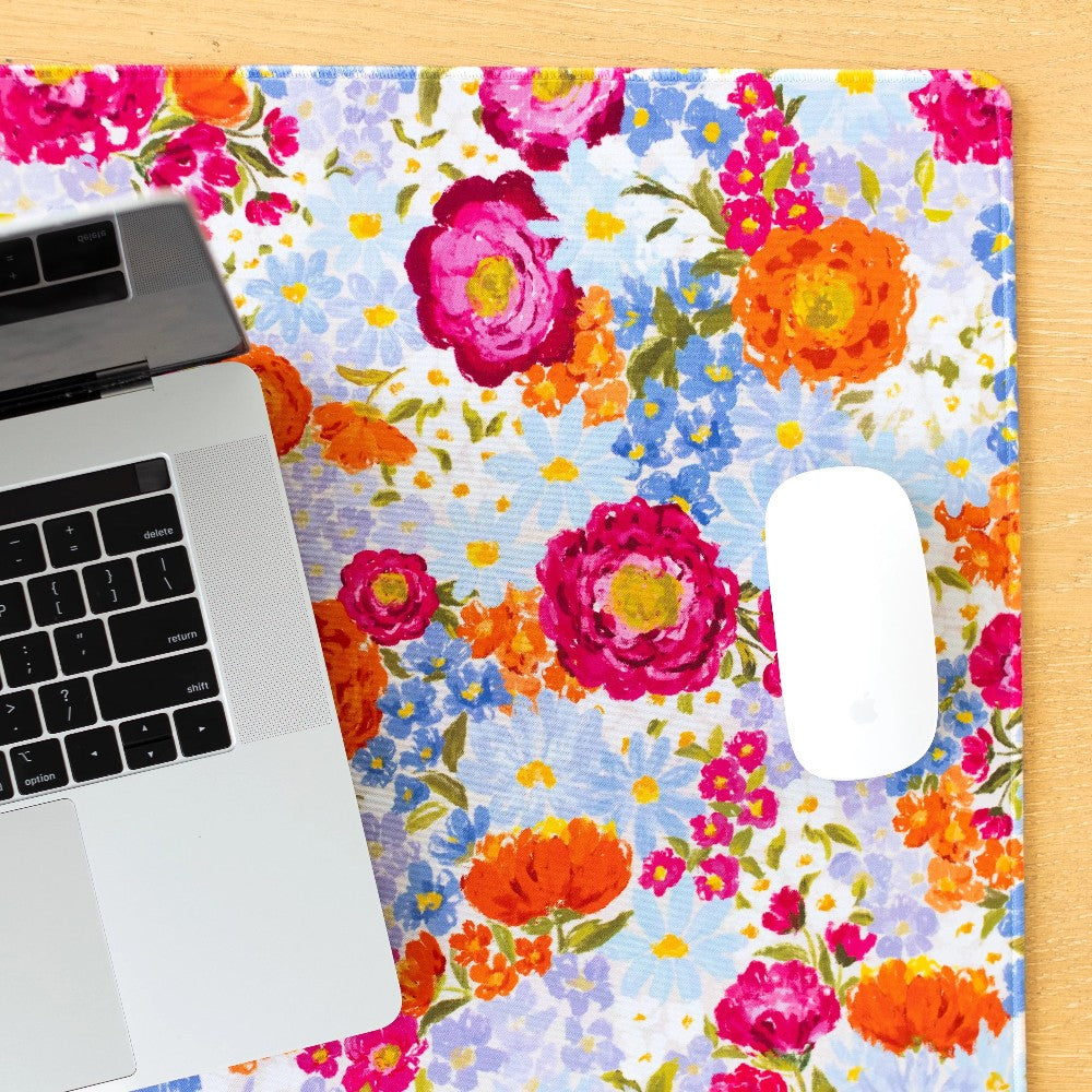 Laptop and mouse on a vibrant floral-patterned surface.