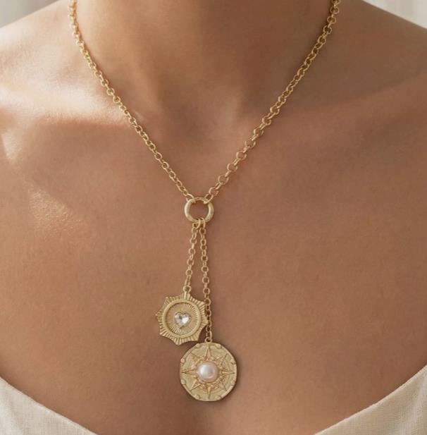 Gold necklace with two round pendants on a person's neck.