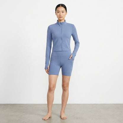Woman in blue activewear posing indoors against a plain background.