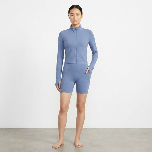 Woman in blue activewear posing indoors against a plain background.