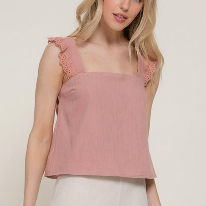 Woman in a pink sleeveless top with lace straps.