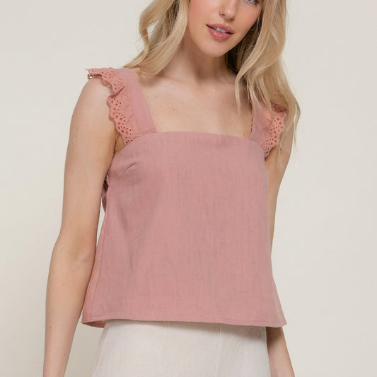 Woman in a pink sleeveless top with lace straps.