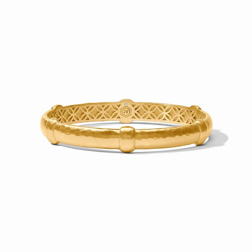 A gold bangle bracelet with an intricate openwork pattern, displayed on a white background.