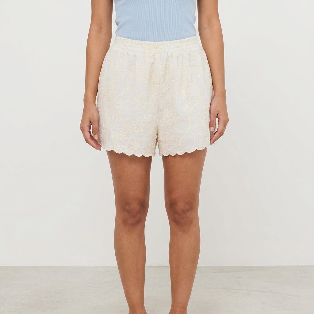 Person in a blue top and cream shorts with scalloped edges.