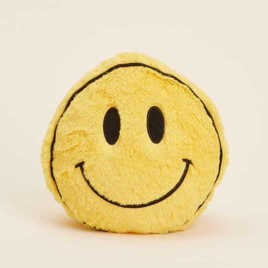 Yellow fuzzy smiley face cushion on a light background.