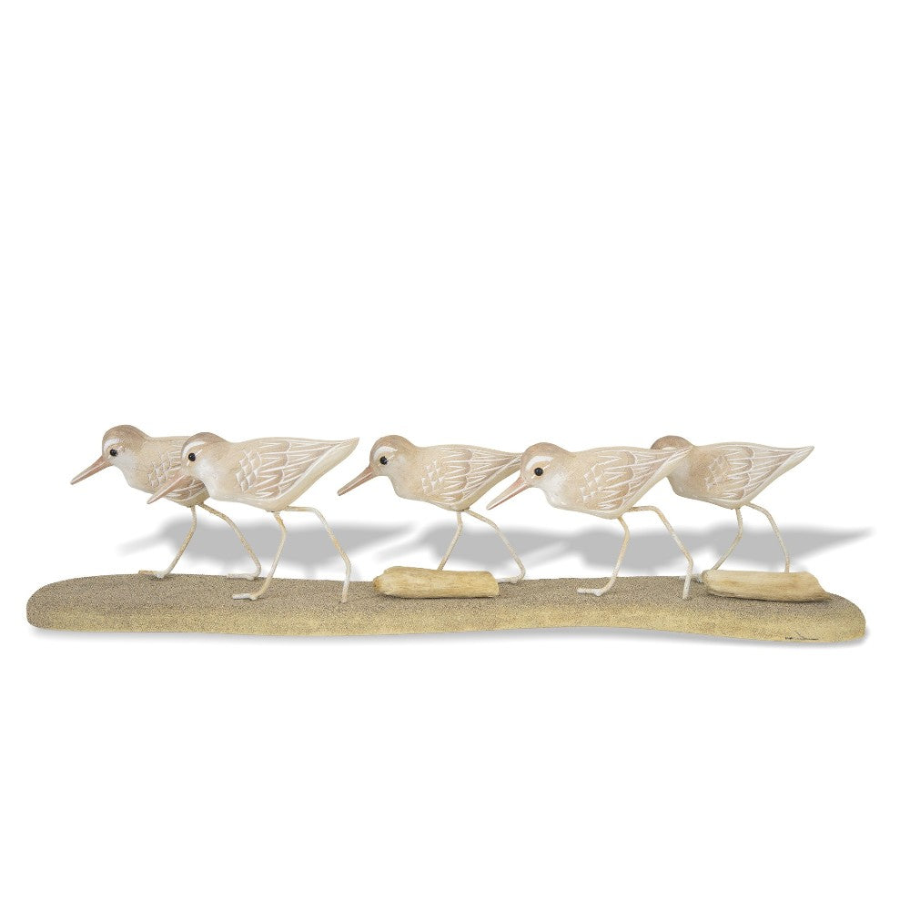 Wooden sandpiper sculptures on a sandy base.