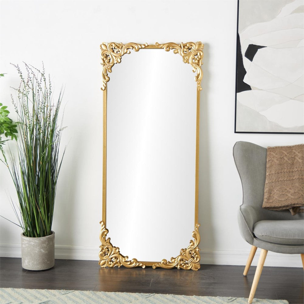 Elegant gold-framed mirror beside plants and armchair.