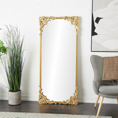 Elegant gold-framed mirror beside plants and armchair.