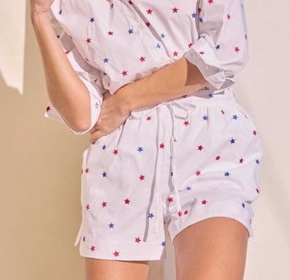 Person in star-patterned shirt and shorts, hand on chin.