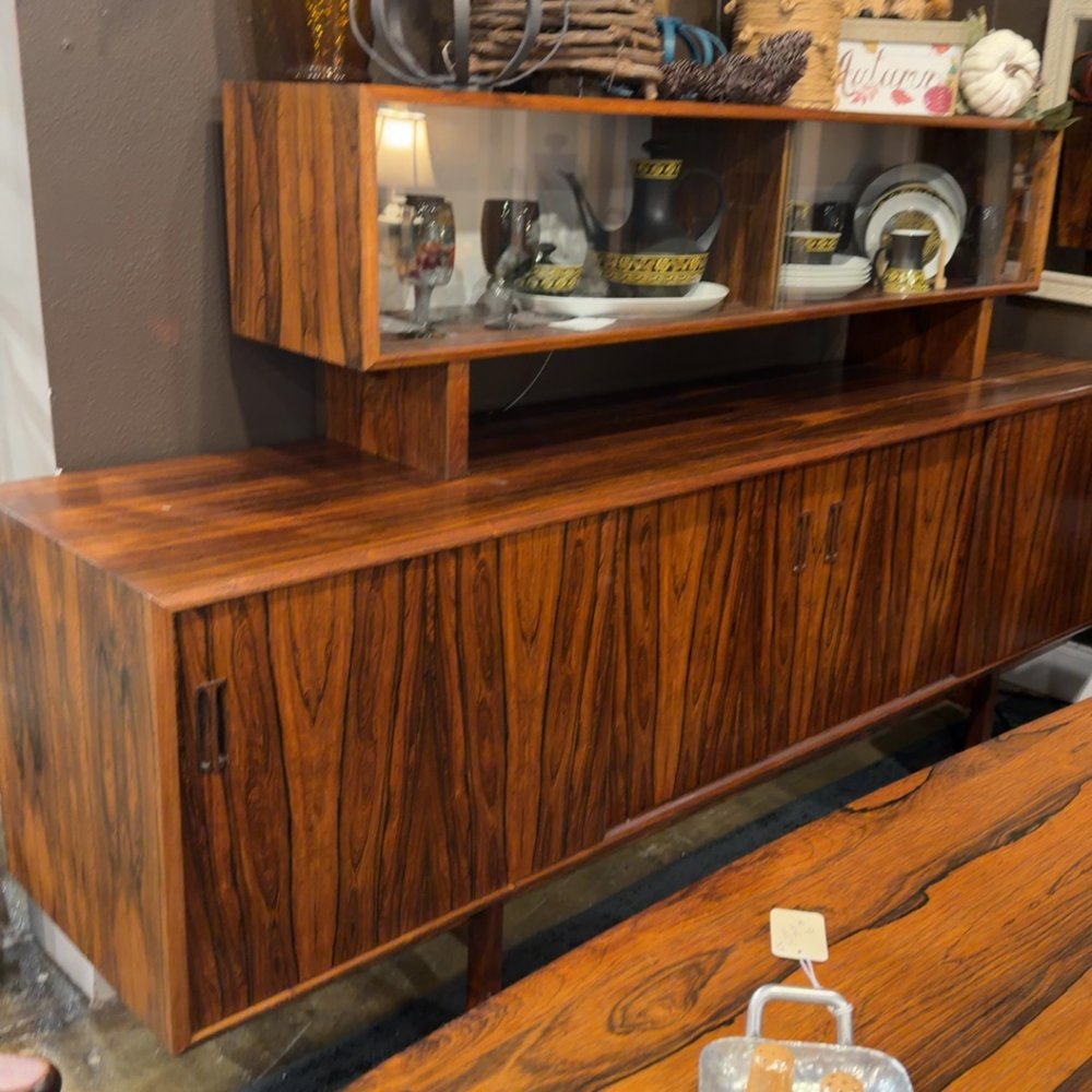 Vintage wooden sideboard and hutch with dishes and decor displayed.