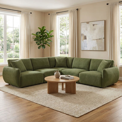 Cozy room with green sectional sofa, plants, and a wooden coffee table on a beige rug.
