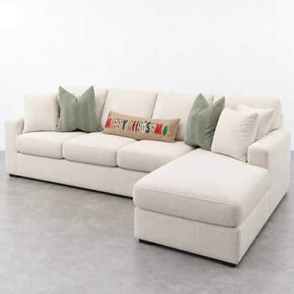 Cream sectional sofa with chaise, festive holiday pillow, and green cushions.