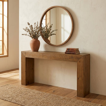 Round mirror, wooden table, vase with branches, stacked books. Minimalist decor.