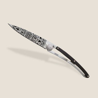 Ornate folding knife with intricate black patterns on the blade.
