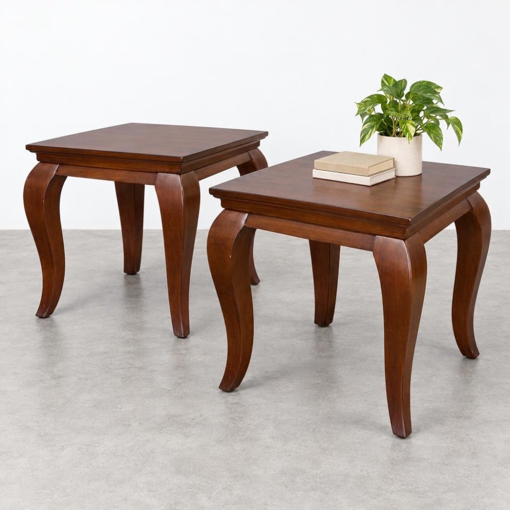 Two dark wooden side tables with curved legs, one topped with books and a potted plant.