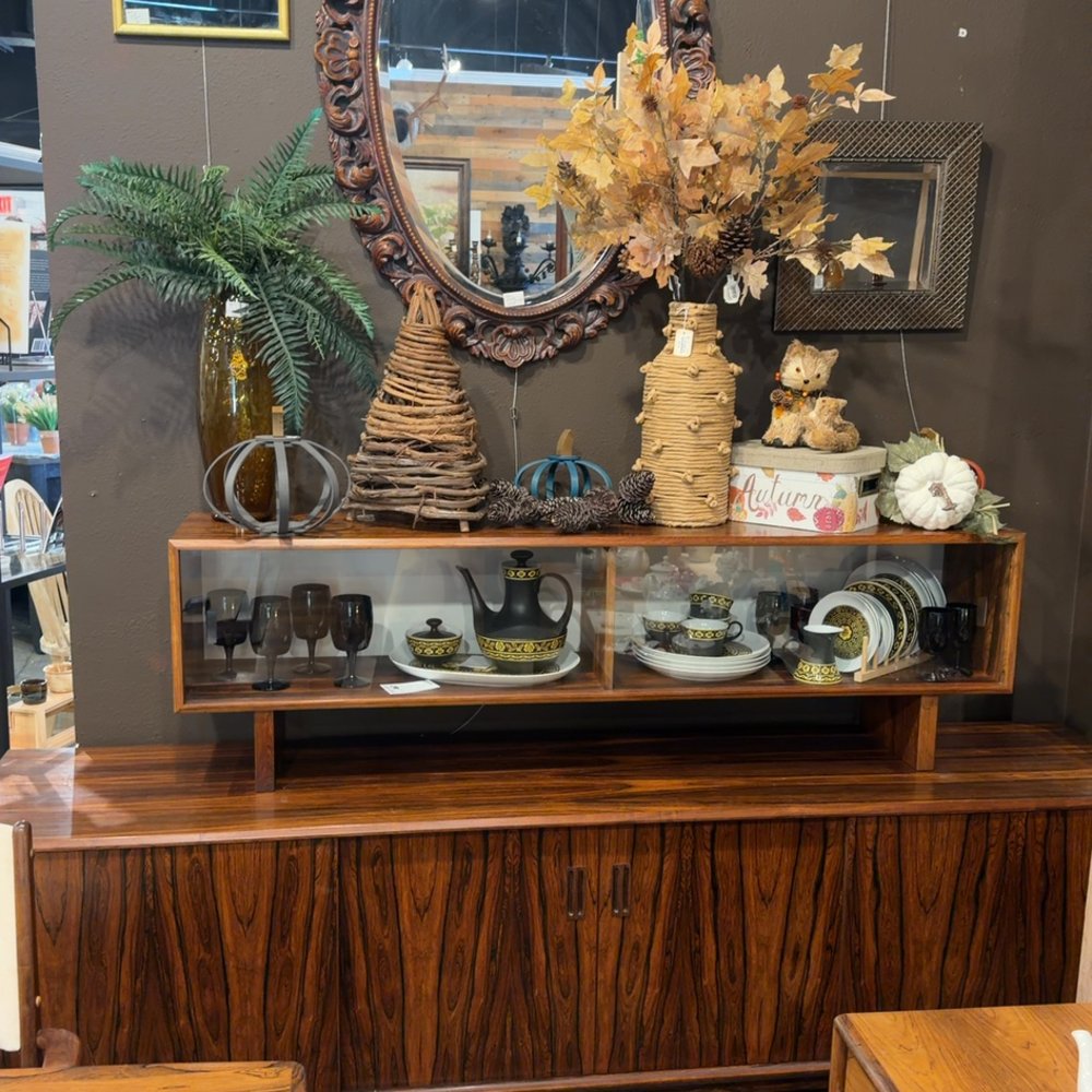 Wooden cabinet with autumn decor and vintage dishes on display.