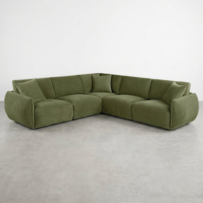 Green L-shaped sectional sofa on a smooth concrete floor.