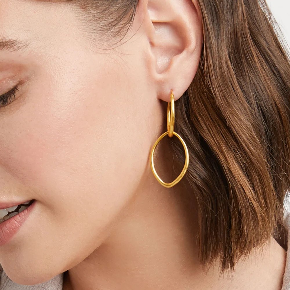 Close-up of a woman wearing a dangling gold hoop earring.