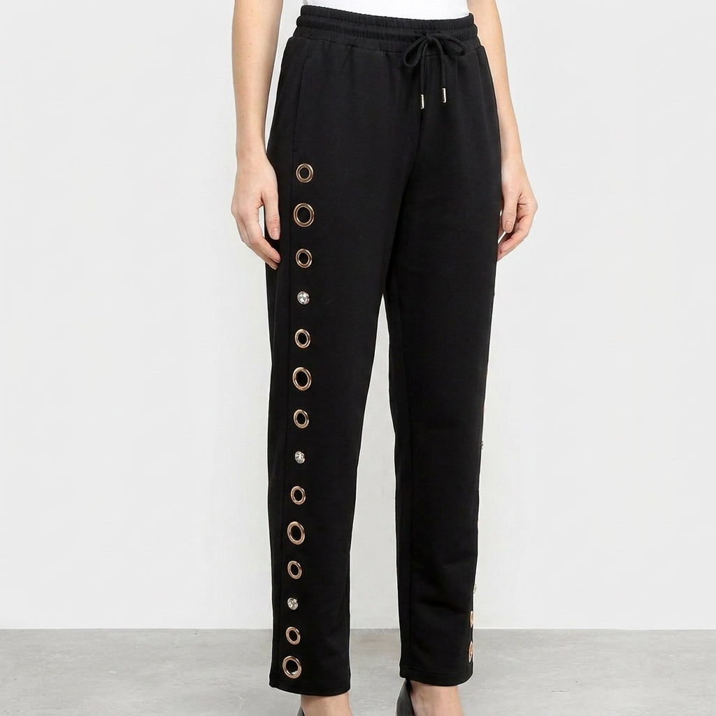 Black pants with decorative grommets along the leg.