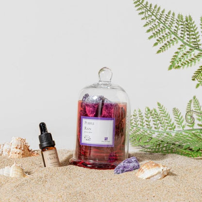 Aromatherapy set with purple stones and essential oil on sand with shells.