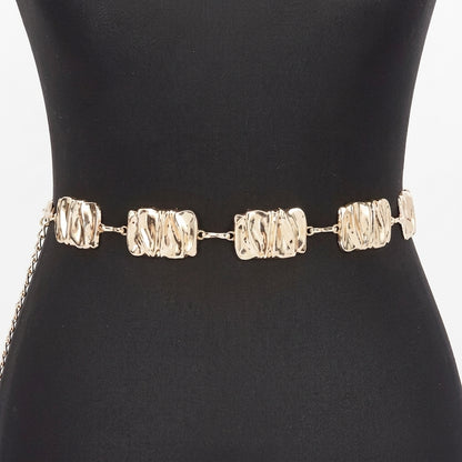 Gold chain belt with textured links on black mannequin.