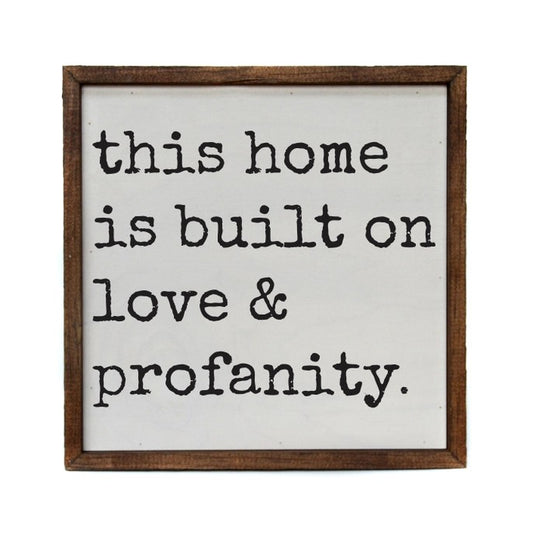 Framed sign reading "This home is built on love & profanity."