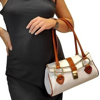 Person in black dress holding a stylish white handbag with brown accents.