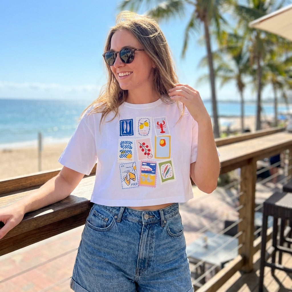 Smiling woman in casual outfit by the beach, sunny day.