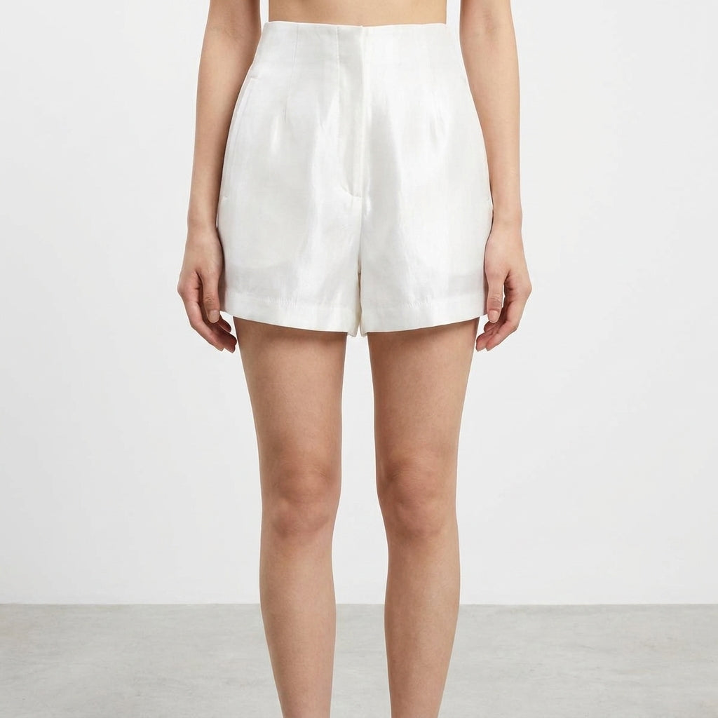 A person wearing white high-waisted shorts on a plain background.