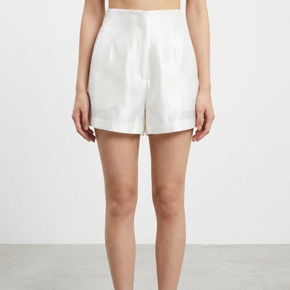 A person wearing white high-waisted shorts on a plain background.