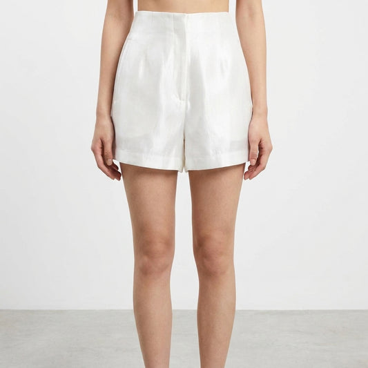 A person wearing white high-waisted shorts on a plain background.